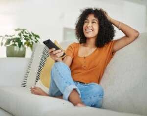 Shot of a young woman relaxing on the sofa and watching tv